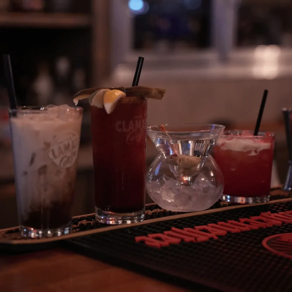 Caesars, a martini and cocktails lined up on the bar rail