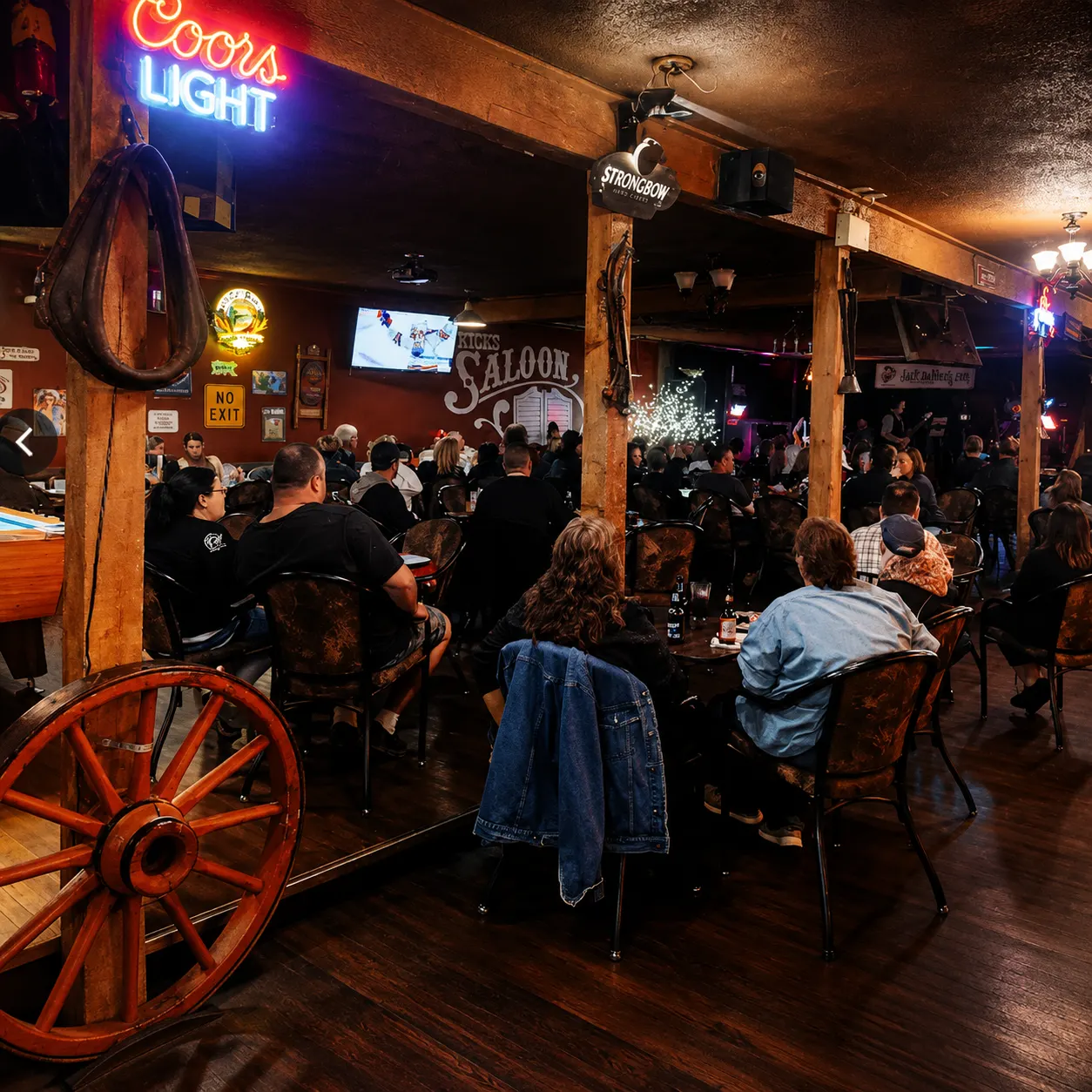 A packed house at Kicks Saloon with live music, wood beams and neon signs